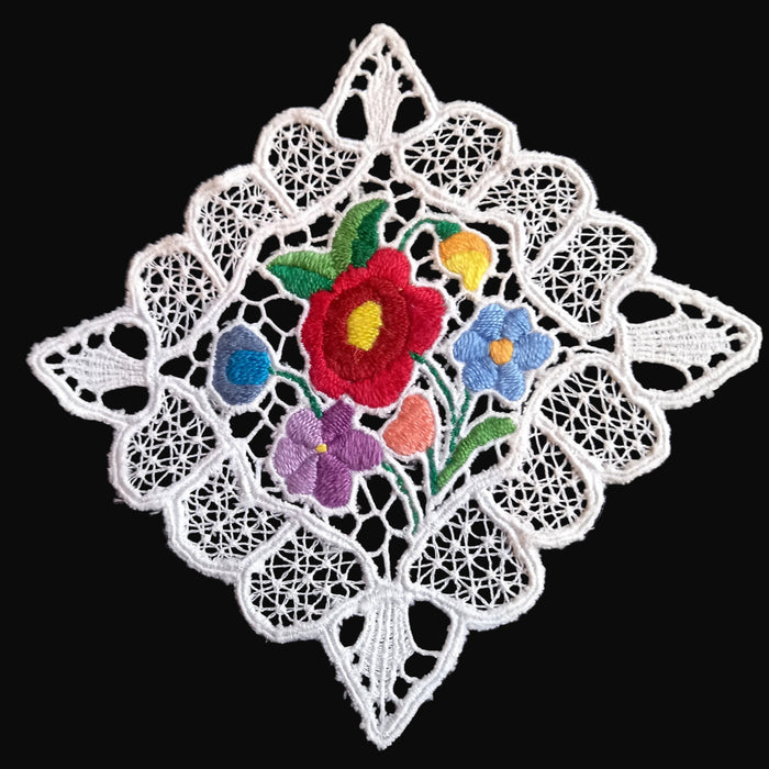 Decorative lace coaster doily with embroidered flowers on a black background, hungarian kalocsa design