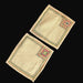 Backside of two beige Hungarian Beregi doily coasters with decorative borders on a black surface