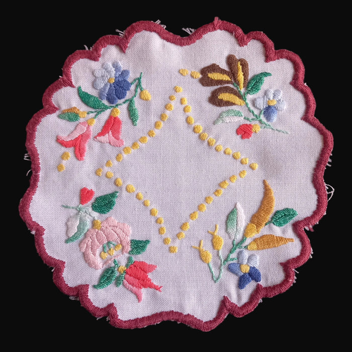 kalocsa style doily from hungary showing flowers and yellow peppers with a maroon border