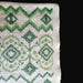 Close-up of cross-stitched green pattern on white fabric with a black border. hungarian folk art