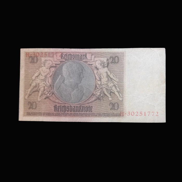 A vintage German 20 Mark banknote with a cream-colored paper background, featuring a central gray circular portrait and red printed serial numbers, displayed flat against a dark background.