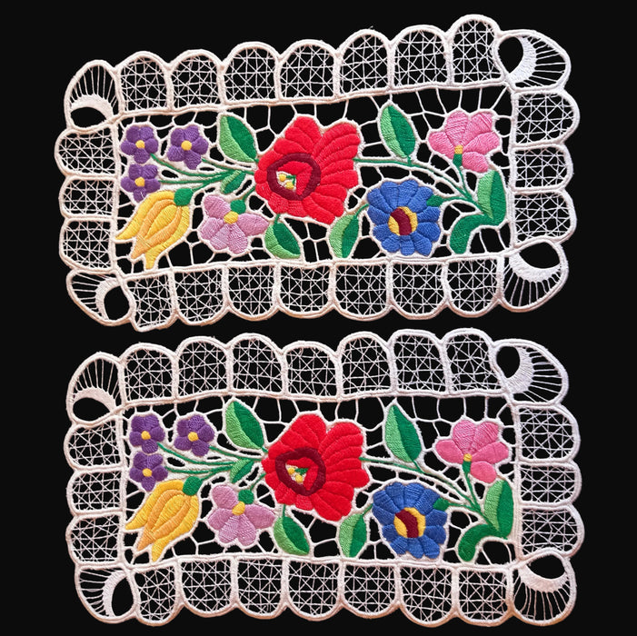 Two embroidered floral doilies with colorful flowers on a black background