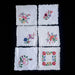 Set of six embroidered floral hungarian kalocsa napkin doilies on a dark surface