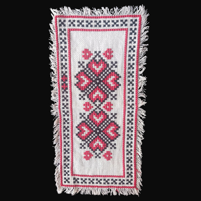 Embroidered Hungarian textile with heart pattern on a dark surface