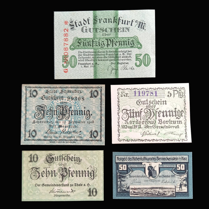 Collection of vintage German notgeld pfennig banknotes on a dark fabric background