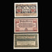 Three vintage German banknotes displayed on a black background