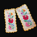 Two yellow hand embroidered Hungarian Kalocsa floral designs on a dark fabric background