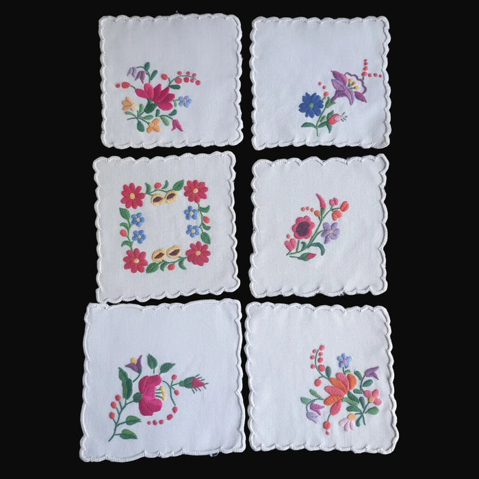 Set of six embroidered floral handkerchiefs on a dark surface