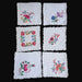 Set of six embroidered floral handkerchiefs on a dark surface