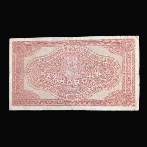 A vintage hungarian 2 Korona banknote with red printed text and ornate border details on aged off-white paper, displayed flat against a dark navy background.