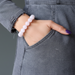 Person wearing a pink rose quartz beaded bracelet on a gray background