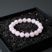 Pink beaded bracelet on a bed of black rice in a dark container