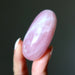 Hand holding a pink rose quartz stone against a dark background 