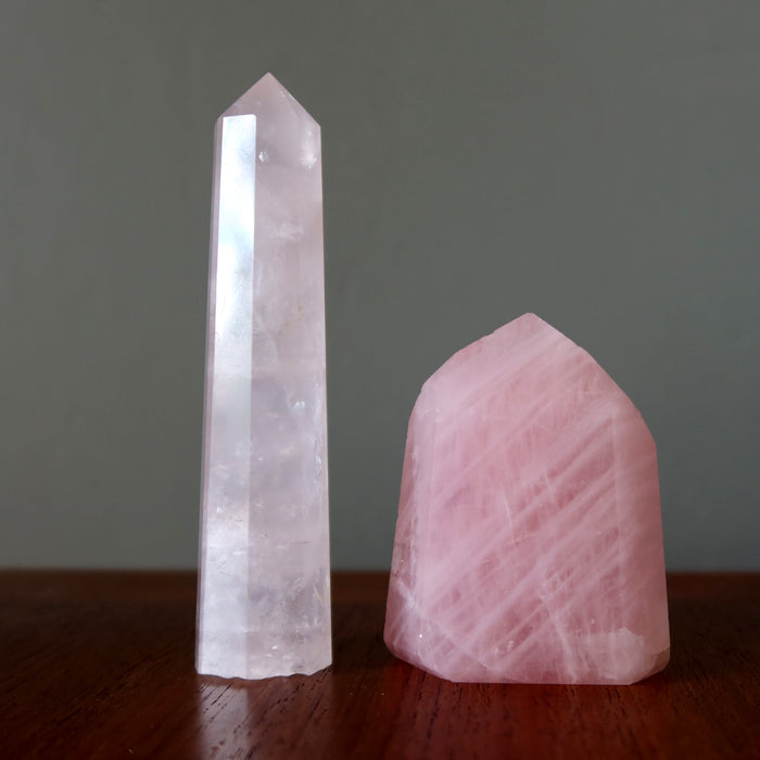 Crystal tower and pink rose quartz  crystal on a wooden surface with a dark background