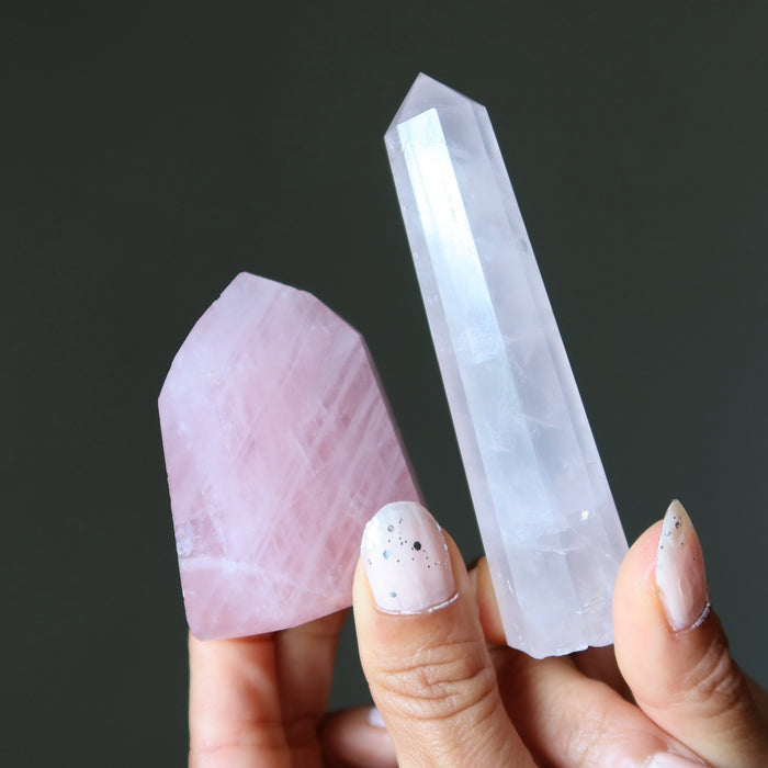 Hand holding a pink  rose quartz against a dark background