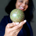 Person holding a green ruby fuchsite stone against a dark background