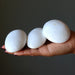 Three white Scolecite held in a hand against a dark background