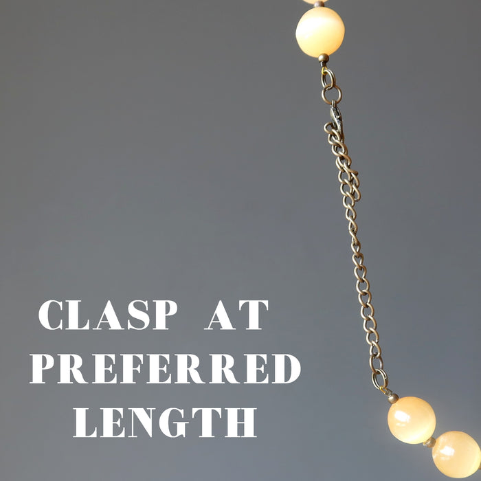 selenite Necklace with spherical beads and chain on a gray background