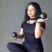 Woman holding two Shungite stones in each hand against a gray background