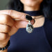 Person holding a silver pendant with a dark  Elite Shungite