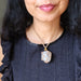 Close-up of a person wearing a necklace with a large smoky quartz necklace.