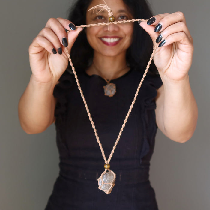 Woman holding a smoky quartz necklace with a pendant against a neutral background