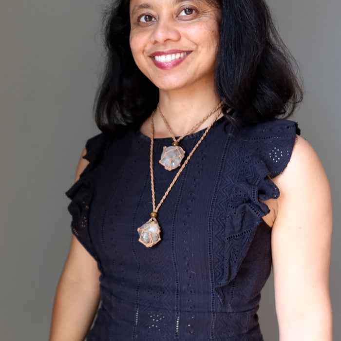 Woman wearing a black dress with ruffled shoulders and two smoky quartz necklaces against a gray background