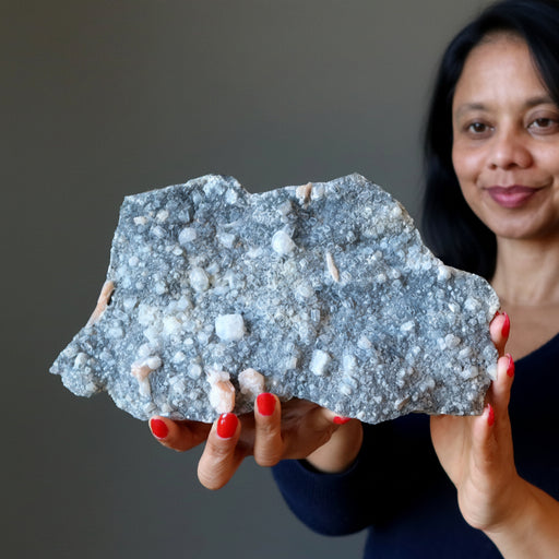 Person holding a large stilbite mineral sample against a neutral background