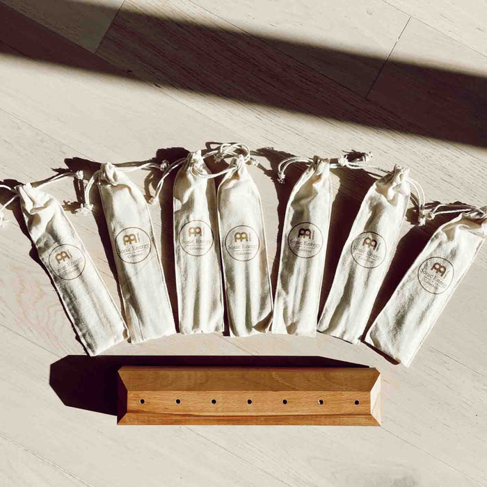 Set of white drawstring bags with a brand logo on a wooden shelf.