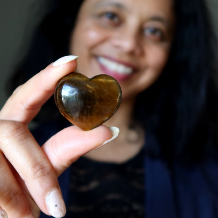 Person holding a heart-shaped brown stone with a blurred background