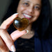 Person holding a heart-shaped brown stone with a blurred background