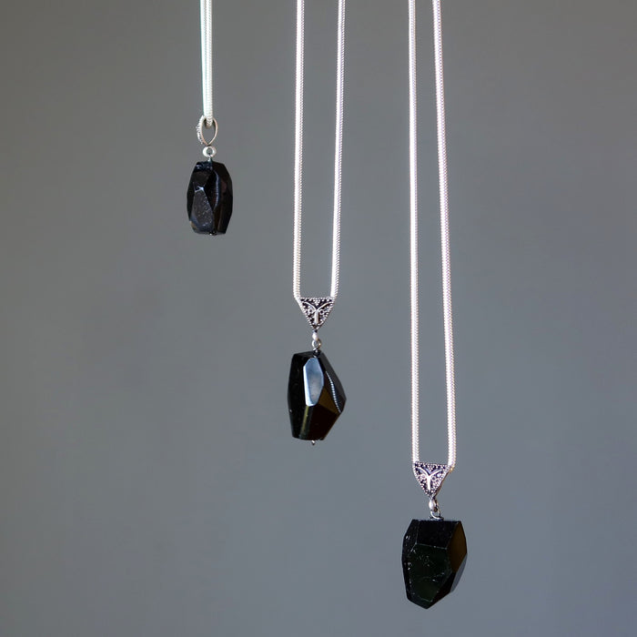 Three black tourmaline pendant necklaces on a gray background