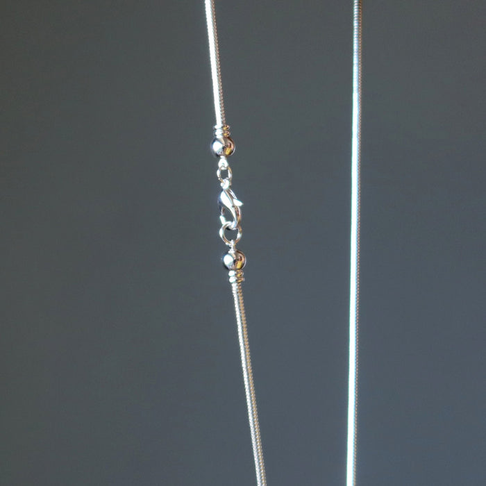 Close-up of a delicate silver necklace on a dark gray background