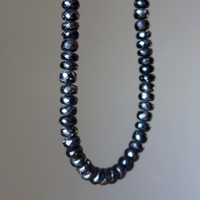 Necklace with dark Tourmaline beads on a plain background