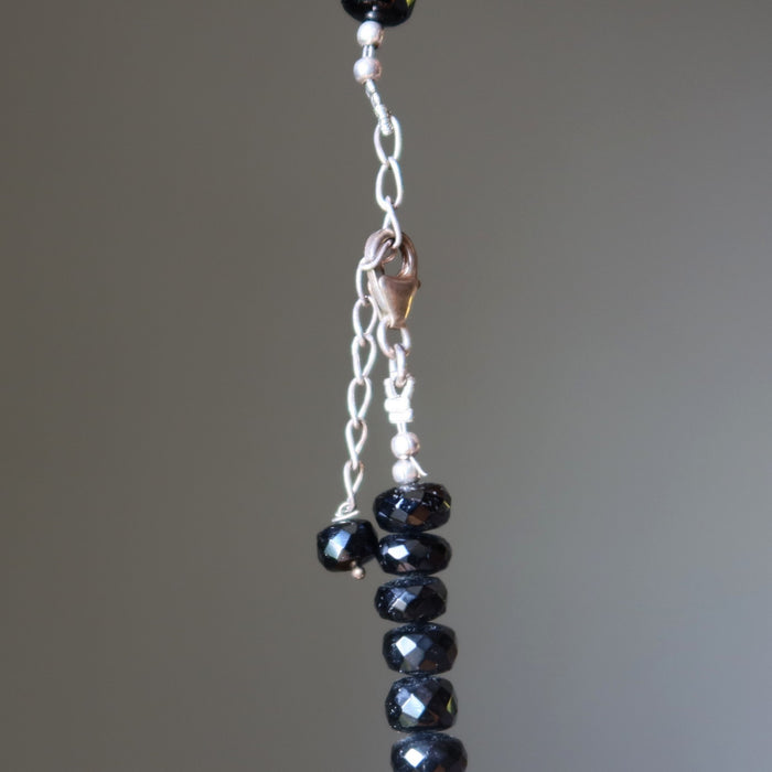 Beaded necklace with black Tourmaline beads and a clasp on a neutral background