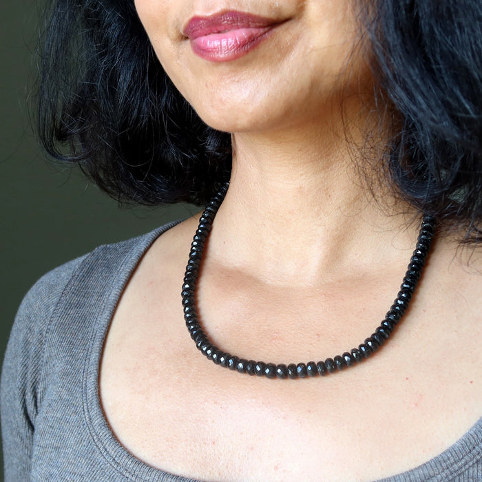 Woman wearing a black Tourmaline beaded necklace against a neutral background