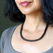 Woman wearing a black Tourmaline beaded necklace against a neutral background