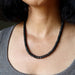 Person wearing a black Tourmaline beaded necklace with a neutral background