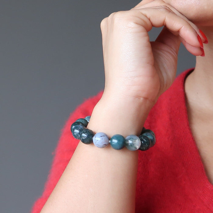 hand on chin wearing green and white moss agate round beaded stretch bracelet