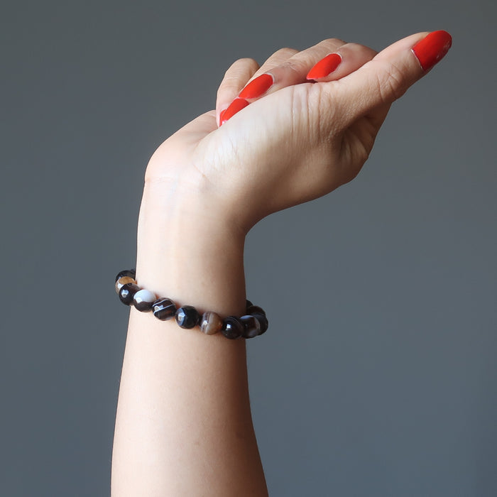 hand wearing banded coffee brown and black agate faceted round beaded stretch bracelets