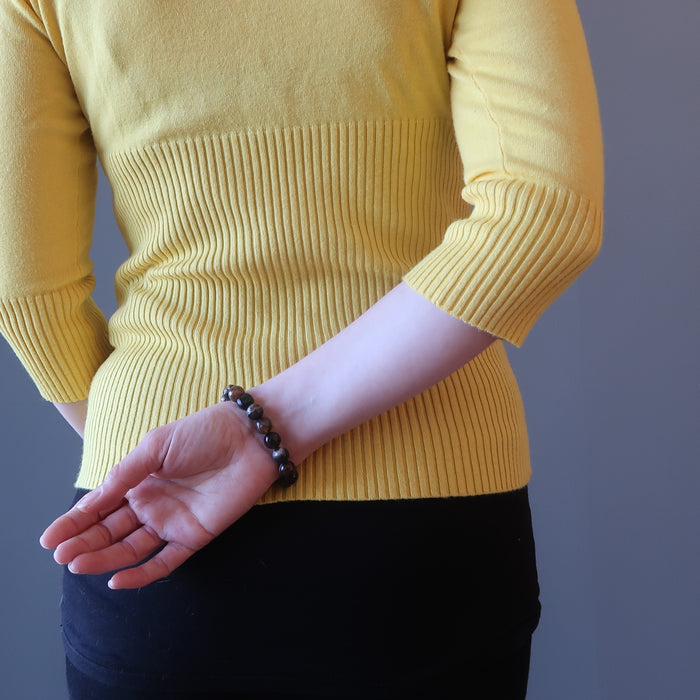 hand at back wearing banded coffee brown and black agate faceted round beaded stretch bracelets