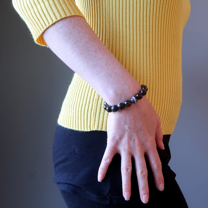 hand on hip wearing banded coffee brown and black agate faceted round beaded stretch bracelets