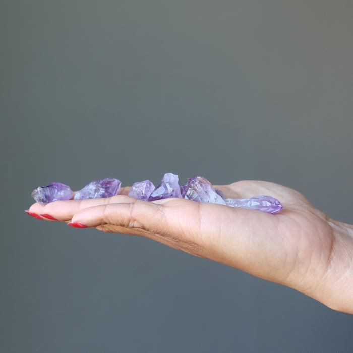 hand holding raw amethyst crystal points