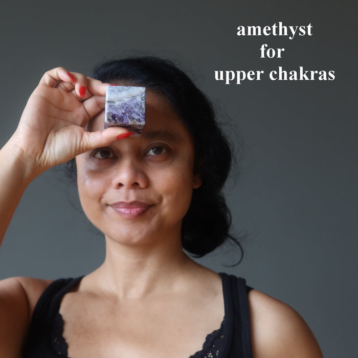 woman holding amethyst cube to her third eye chakra