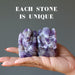 Palm holding Two Amethyst purple Ganesh Elephant Gods. Text says each stone is unique.