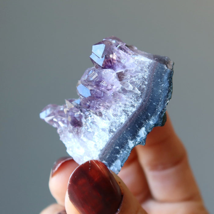 fingers holding amethyst cluster