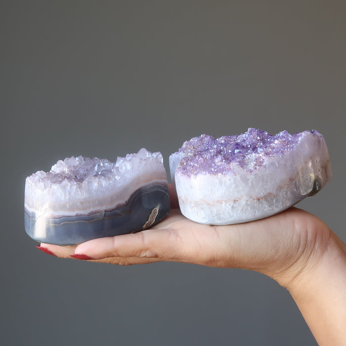 hand holding two 3.0-3.75 Inches violet amethyst heart crystal clusters