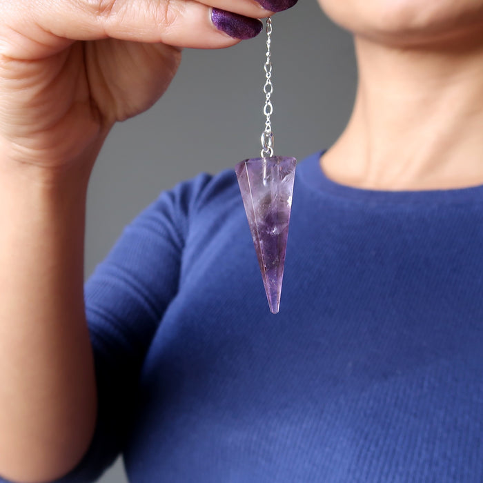 hand holding amethyst pendulum