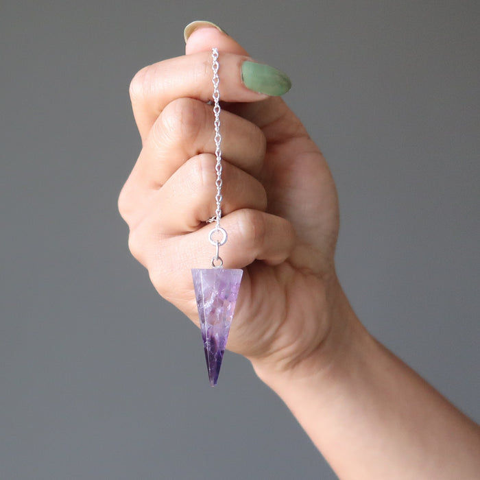 hand holding amethyst pendulum
