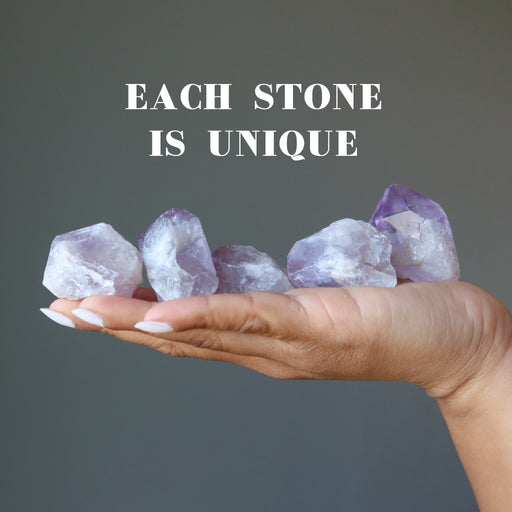 hand holdig five raw purple amethyst points